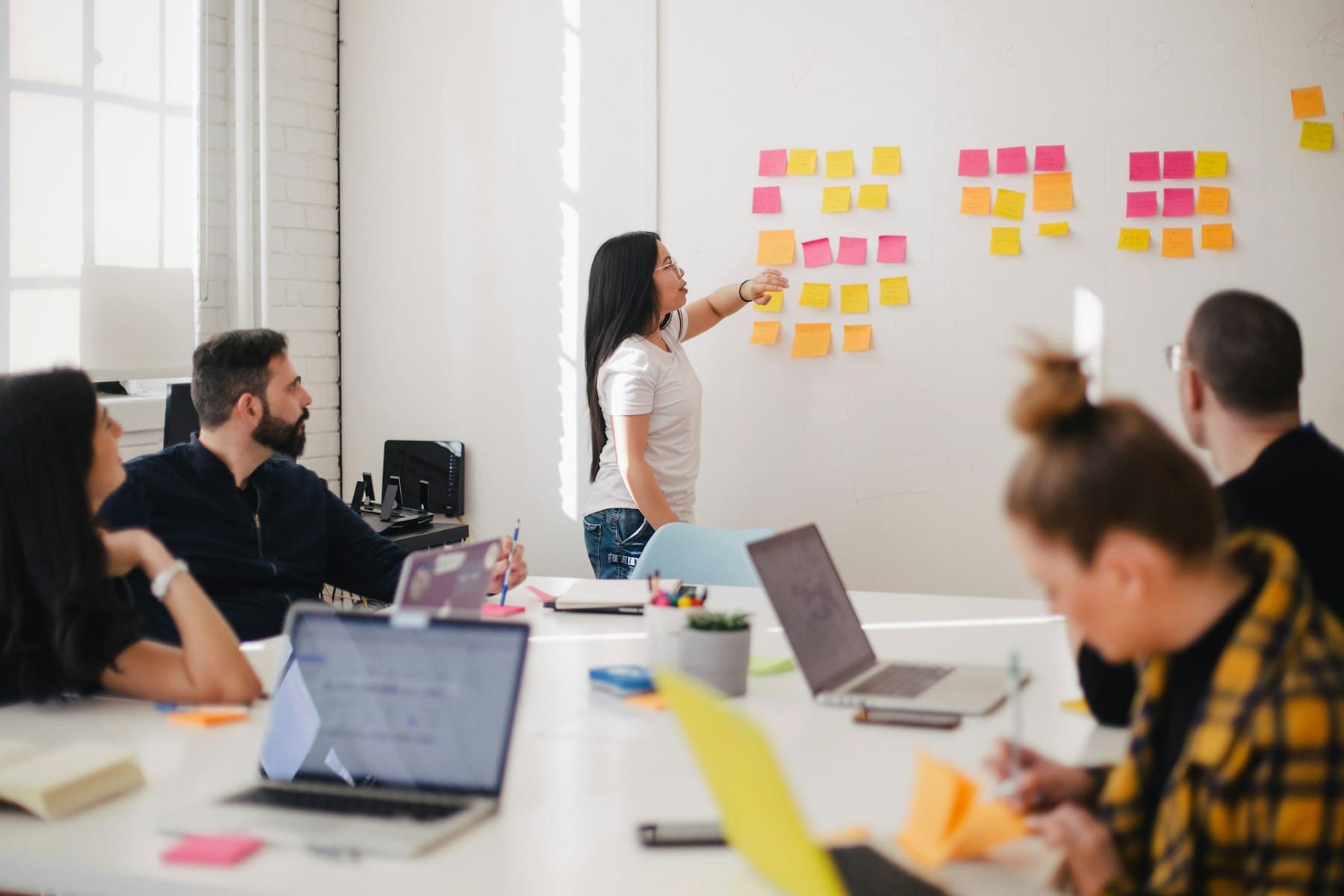 A team watching a colleague arrange sticky notes on a wall